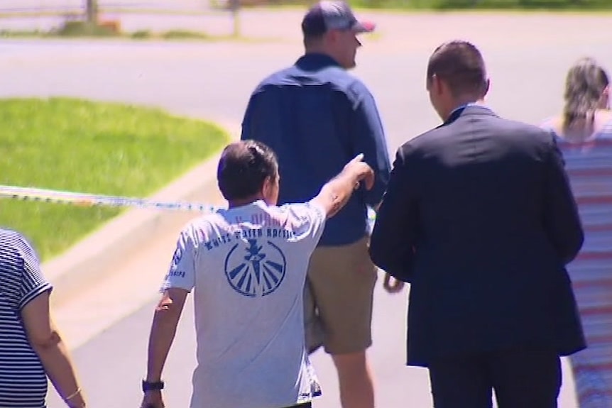 A man points detectives to the house where the invasion occurred.