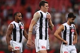 Three Collingwood AFL players walk from the field after losing to GWS.