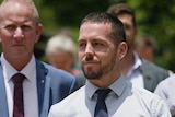 Zachary Rolfe walking out of a court with a group of supporters, as one pats him on the back.