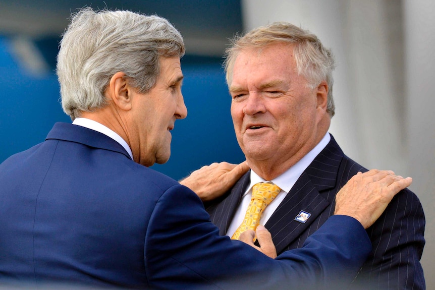 US Secretary of State John Kerry puts his hands on the shoulders of Australia's ex-Ambassador to the US Kim Beazley.