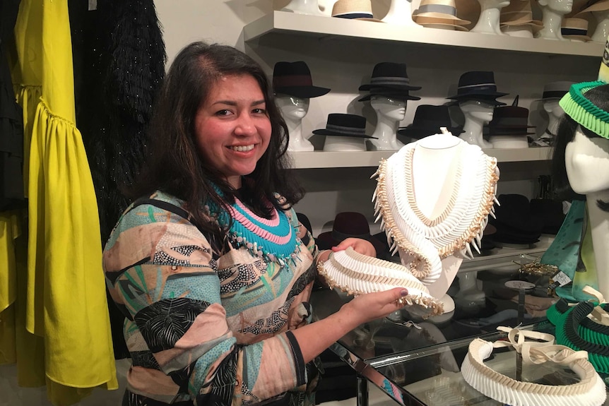 Grace Lillian Lee in a boutique, holding up her designs.