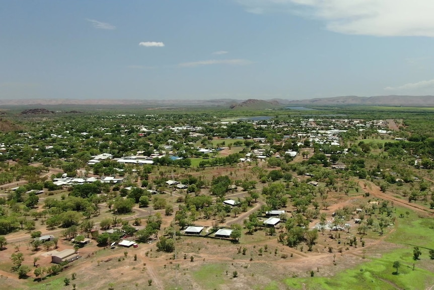 A drone shot above Kununurra, a green flat town, with hills in the far distance.
