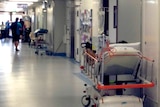 A patient in a Perth hospital bed in a corridor