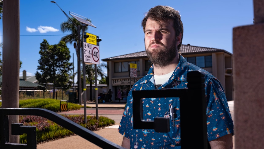 A man stands next to a gate