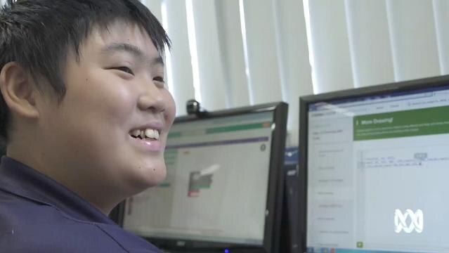 Smiling boy sits at computer