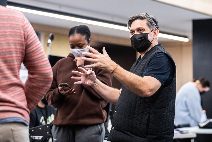 Wesley Enoch directing at rehearsals, Actor Angela Mahlatjie in mask looking at script on phone