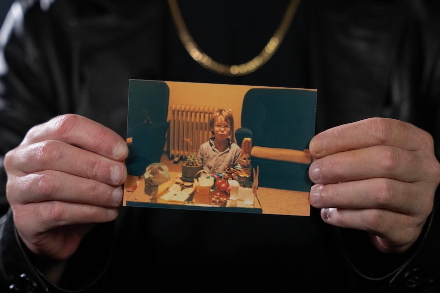 A man's hands hold a photo of a young boy