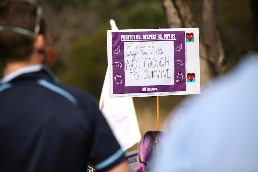 A rally goer holds up a sign saying 'Not enough to survive'