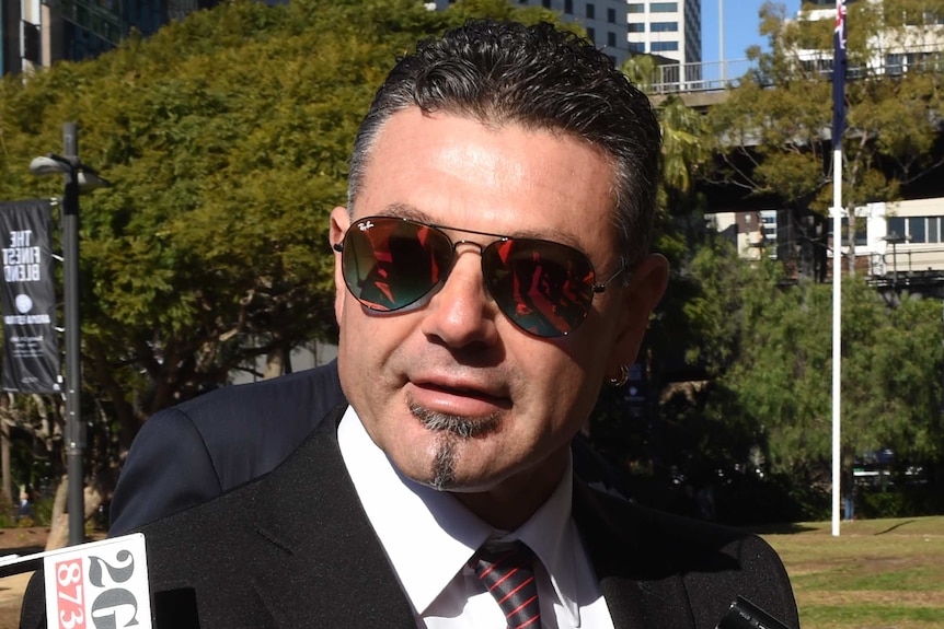 Michael Diamond wearing aviator sunglasses, walking through the media.