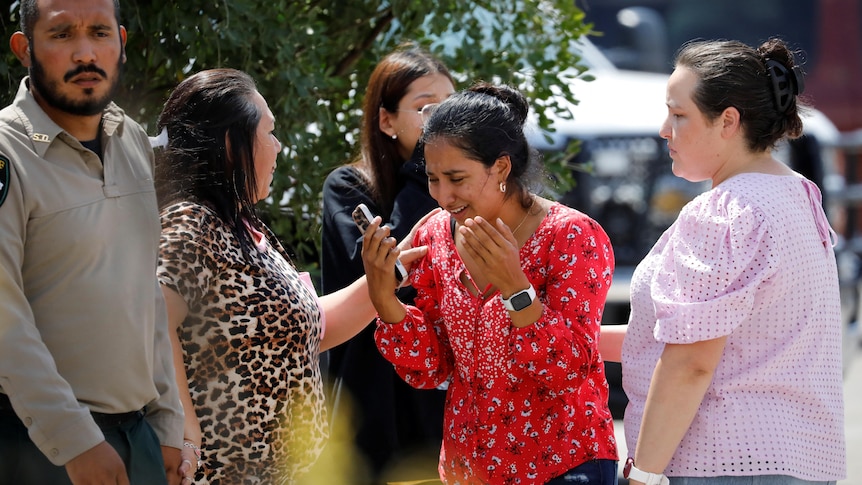 A woman cries surrounded by a group of people