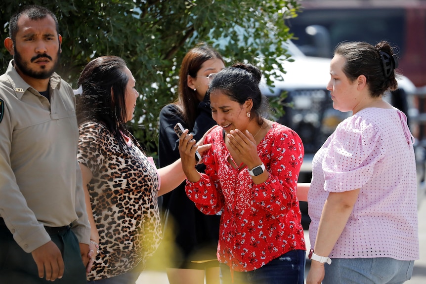 A woman cries surrounded by a group of people