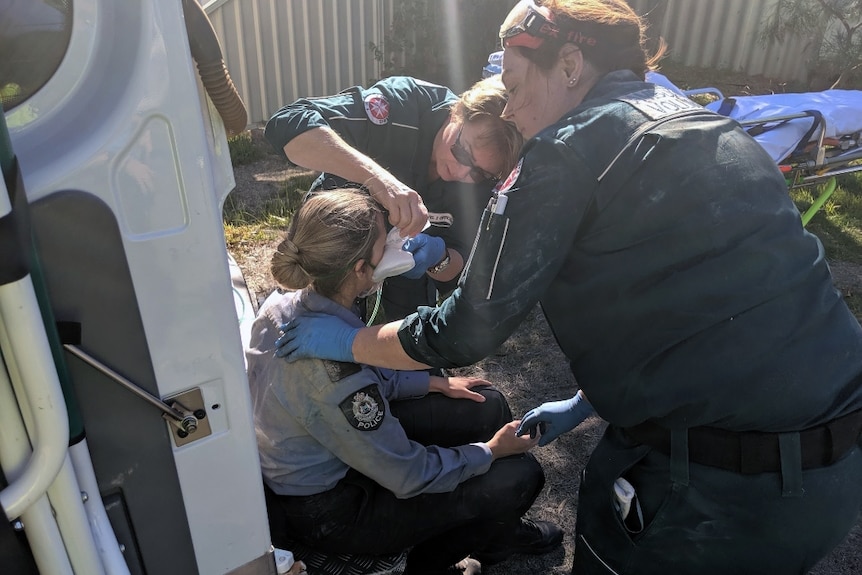 A police officer is assisted by a paramedic after she helped rescue a boy stuck in a chimney in Katanning.