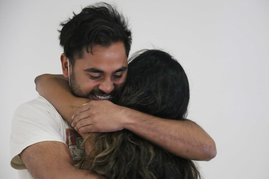 A close up shot of Ruchira hugging his girlfriend in an airport terminal.