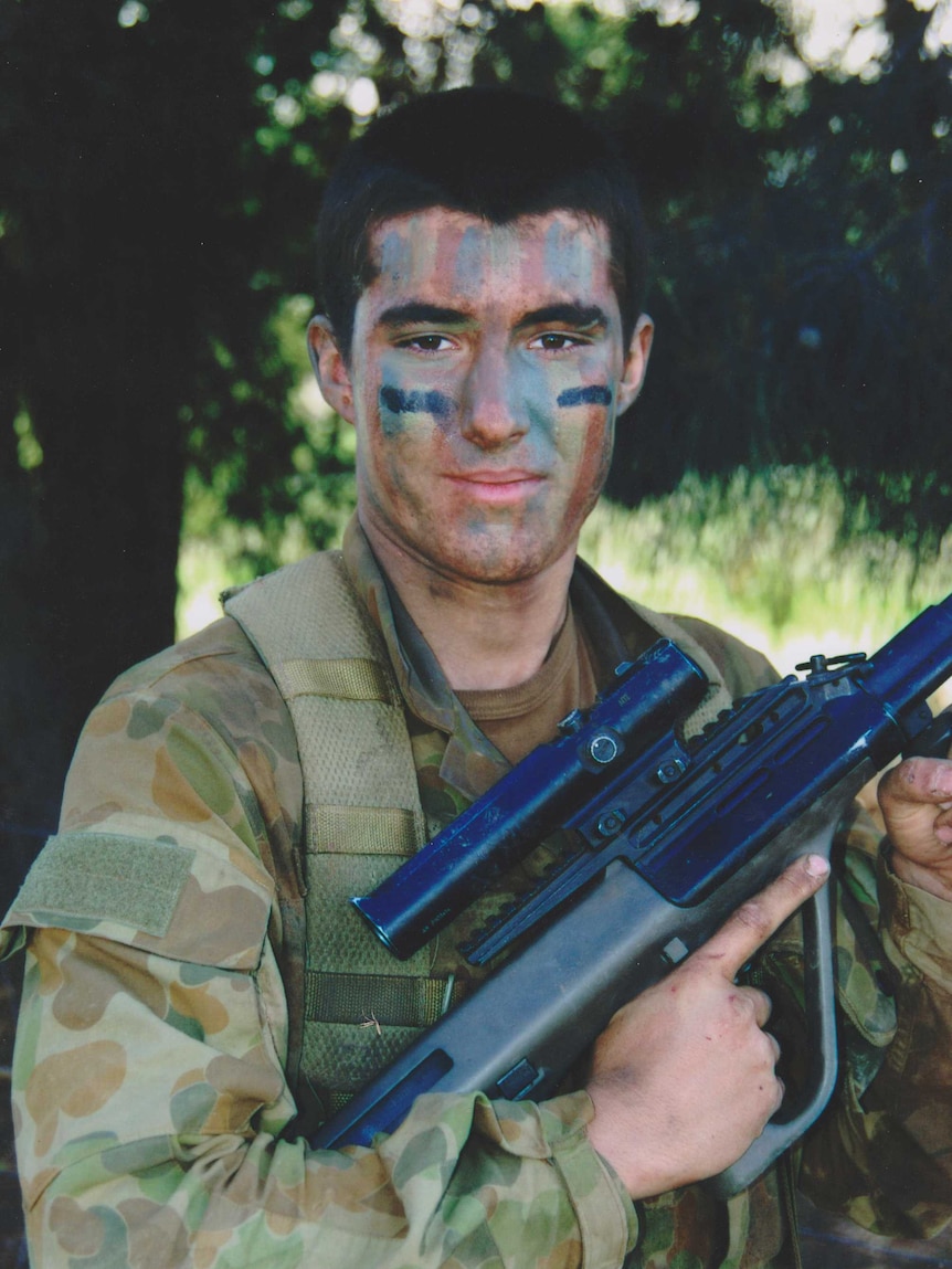 Sapper David Wood in camouflage paint and Army uniform holding a gun