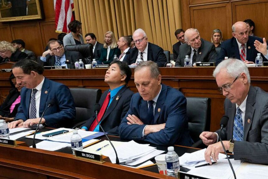 A number of members of congress sit in the chambers reading the impeachment articles