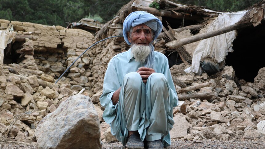 An Afghan man sits near his house that was destroyed in an earthquake
