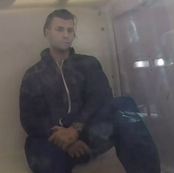 A man sits in the back of a police van
