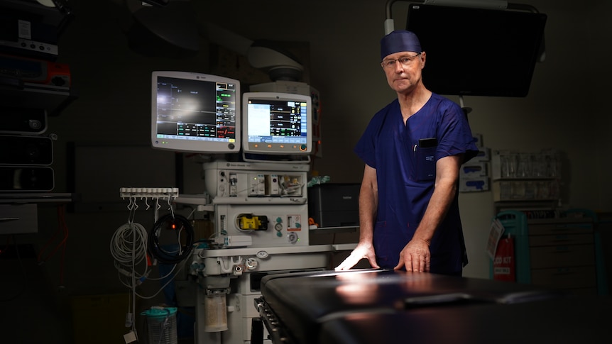 Doctor in blue scrubs standing in an operating theatre.