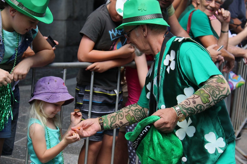 St Patrick's Day parade participant hands out sweets to the crowd