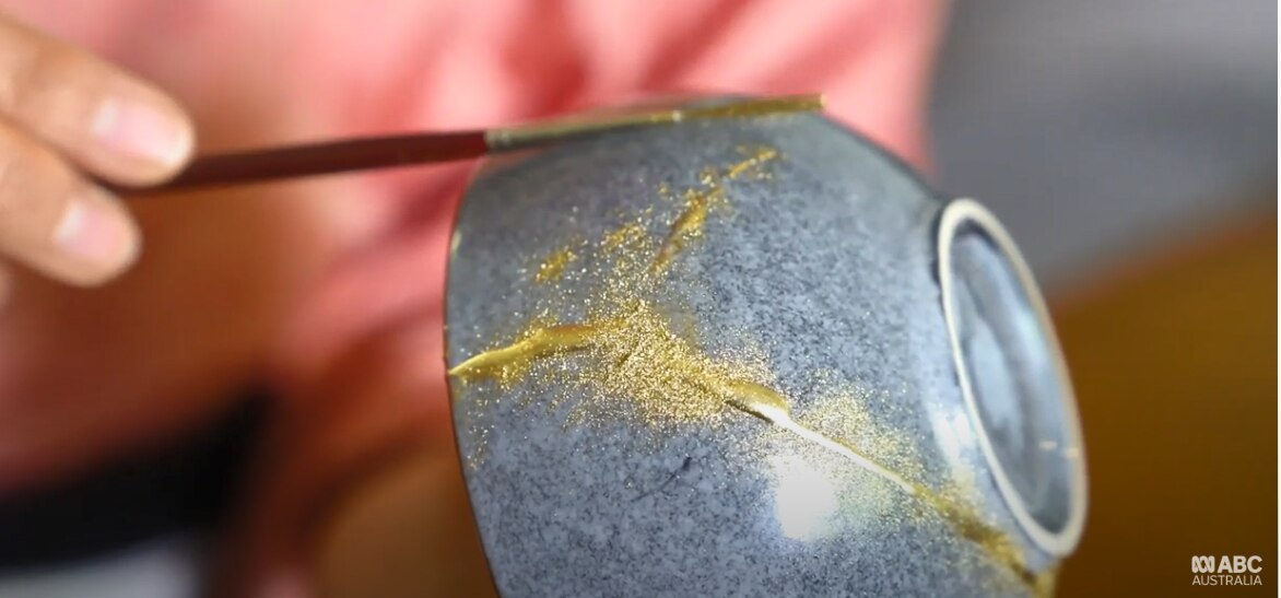 Kintsugi pottery being painted gold with brush