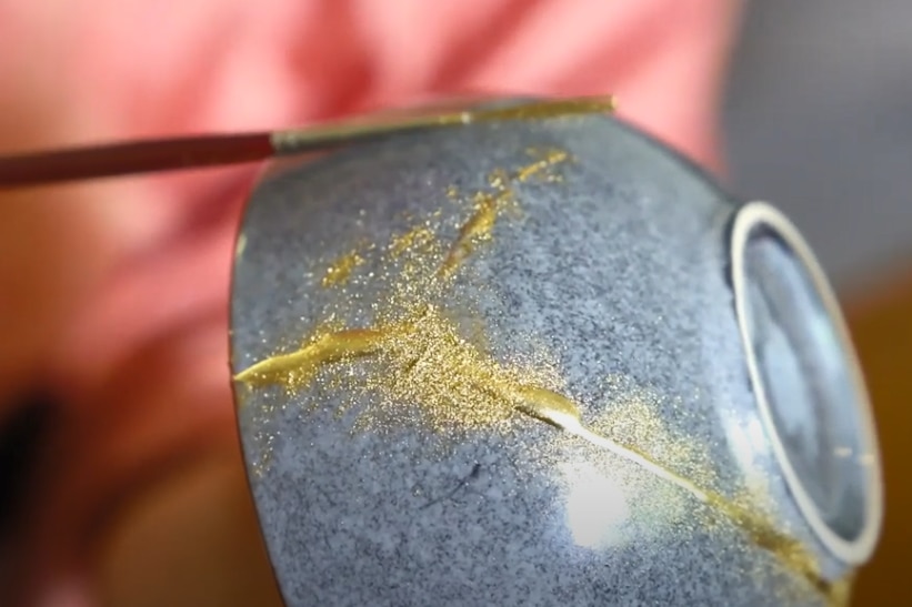Kintsugi pottery being painted gold with brush