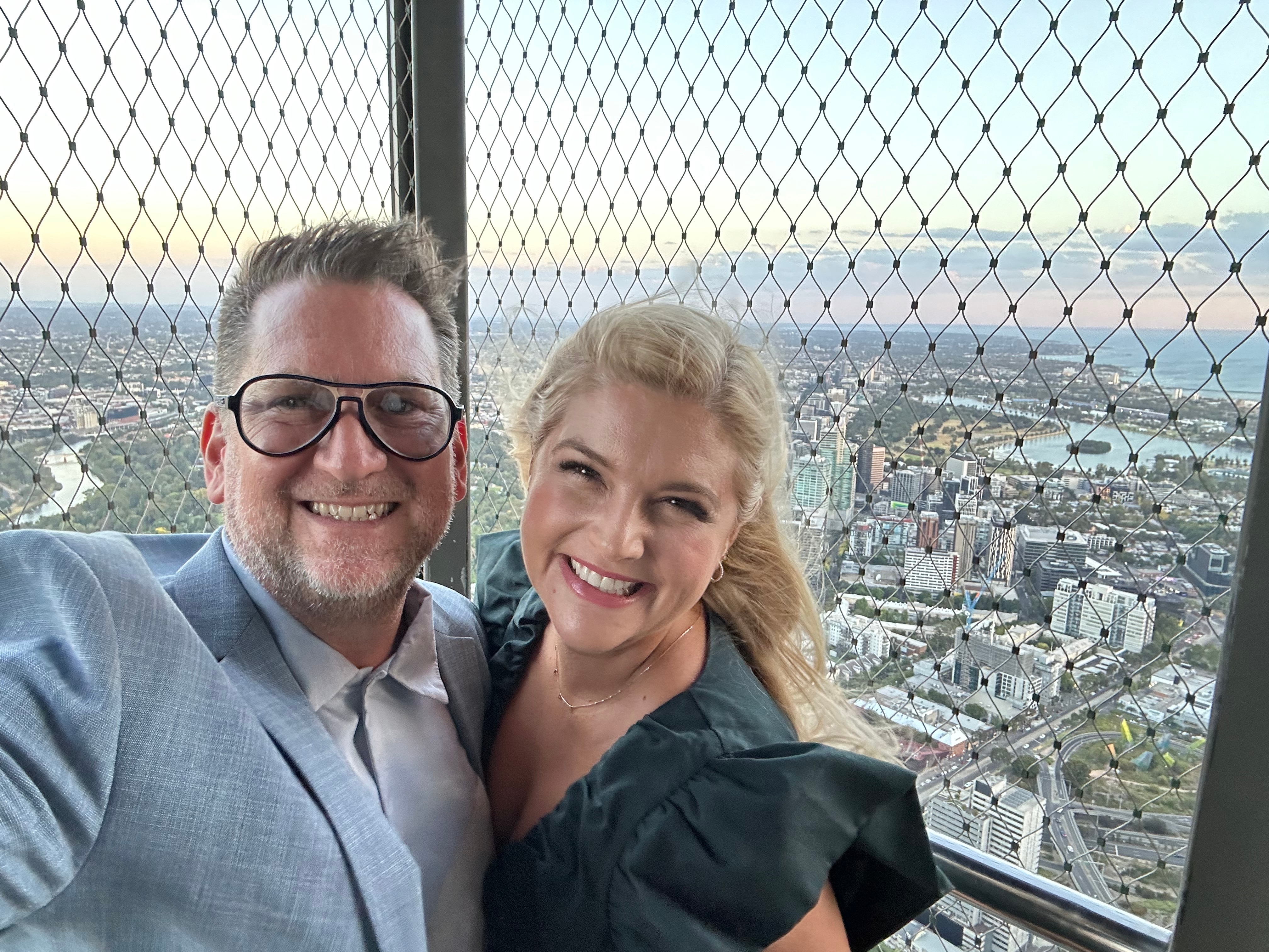 Lucy Durack with her husband Christopher Horsey as they smile for a selfie at the top of a tall building.