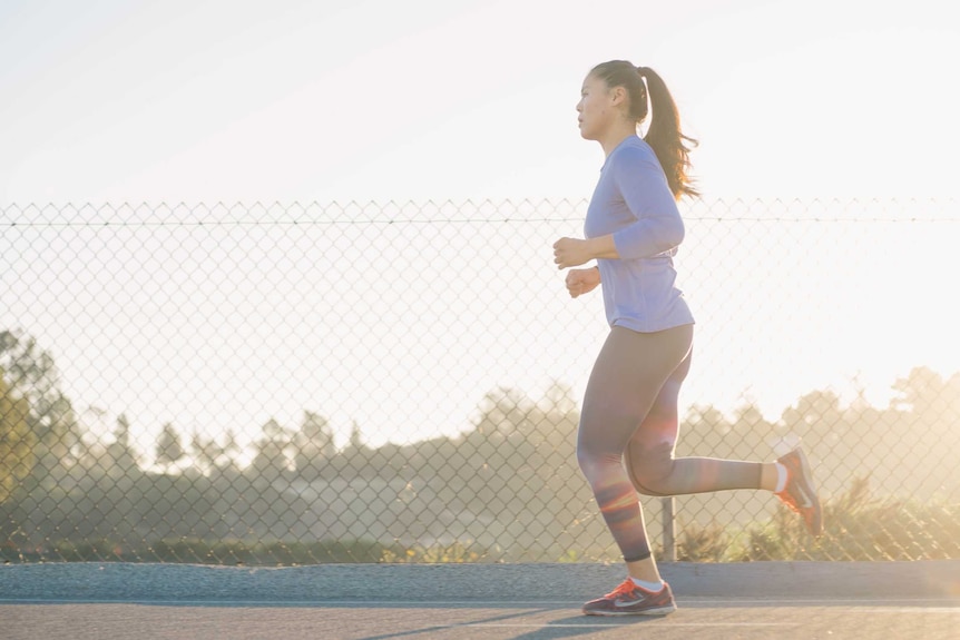 A woman runs on a footpath early in the morning.