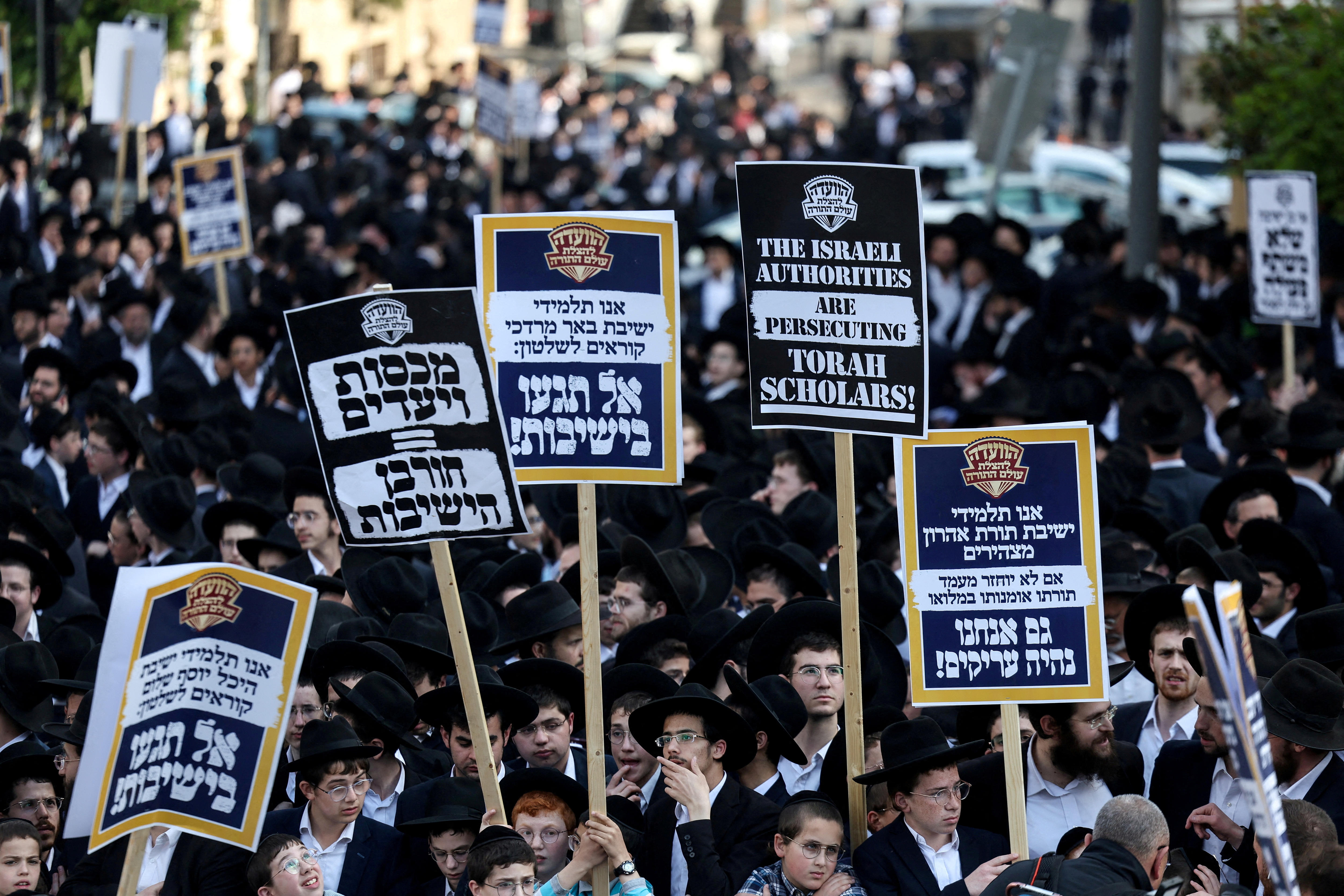 Ultra-Orthodox Jewish men staging a protest where they are holding up banners.