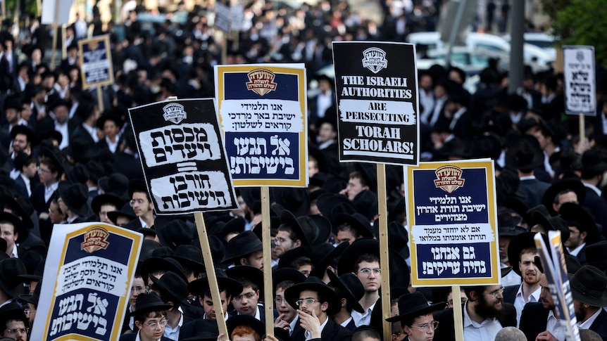 Ultra-Orthodox Jewish men staging a protest where they are holding up banners.
