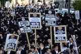Ultra-Orthodox Jewish men staging a protest where they are holding up banners.
