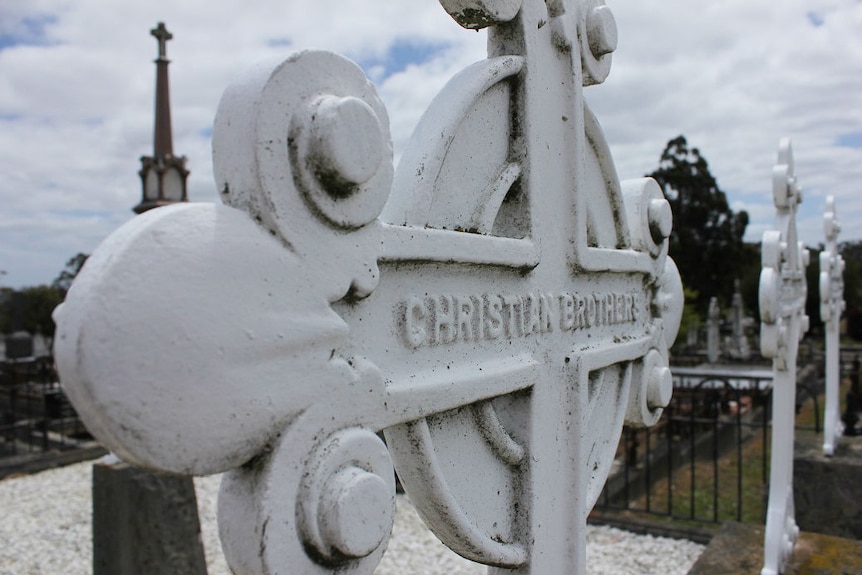 A close-up of a white Celtic cross with the words Christian Brothers written across the centre.