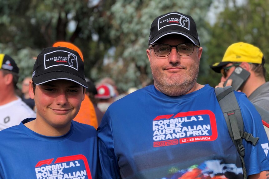 Two men wearing blue Australian Grand Prix t-shirts look at the camera.