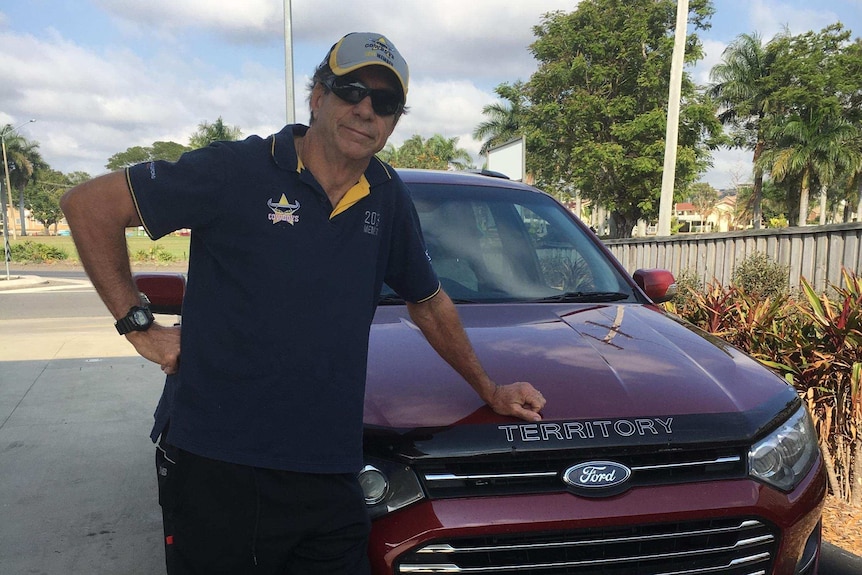 Peter Rowe in front of his car on the road with Cowboys number plates