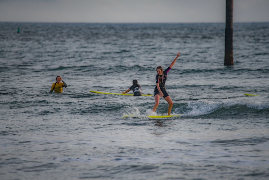 Une jeune fille surfe sur un longboard sur une petite vague dans l'océan