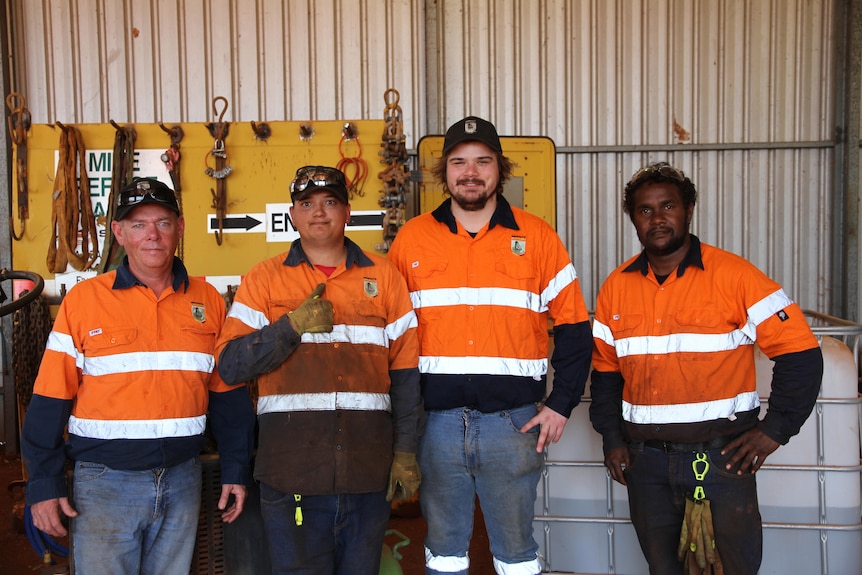 Four men in high vis standing in a row