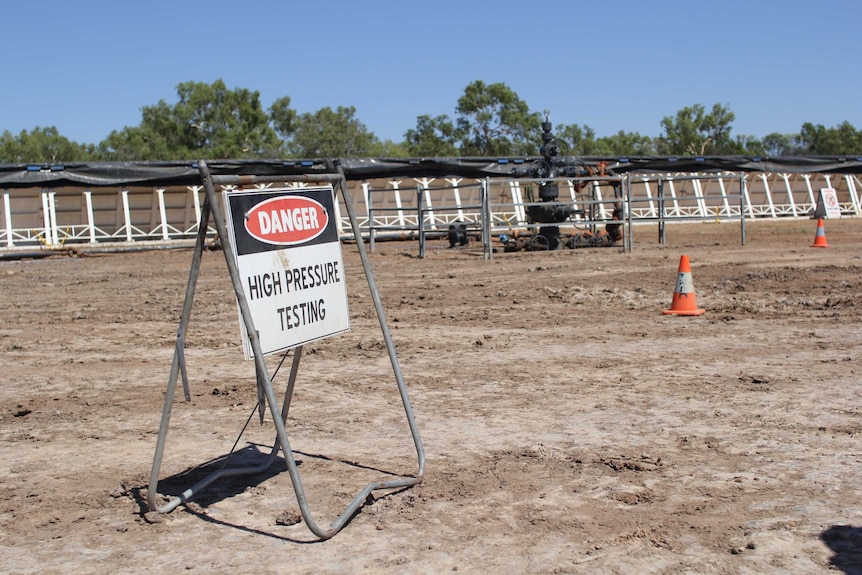 High pressure testing sign near Amungee wellhead, water treatment pond in background