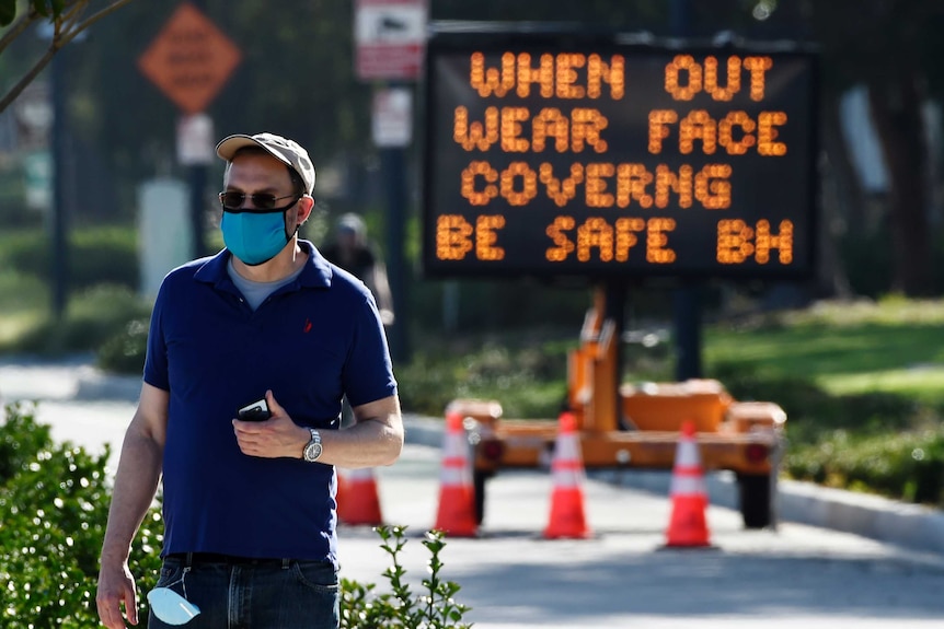 A man in a mask walking along a boulevard