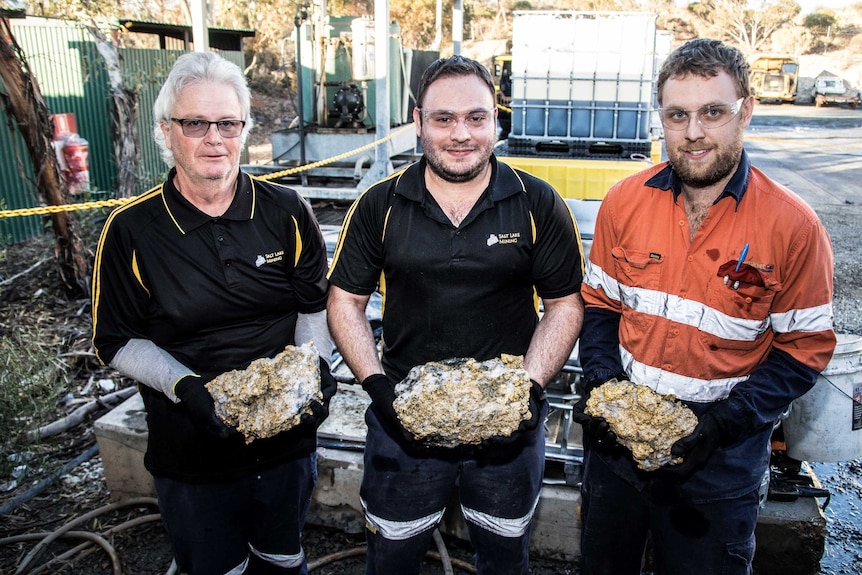 Gold-covered rocks held by mine workers