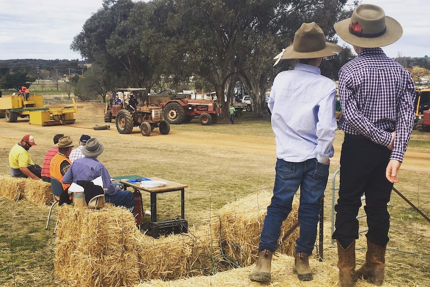 Two children look on at a tractor pull at an agricultural show.