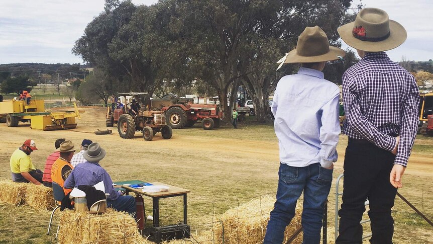Two children look on at a tractor pull at an agricultural show.