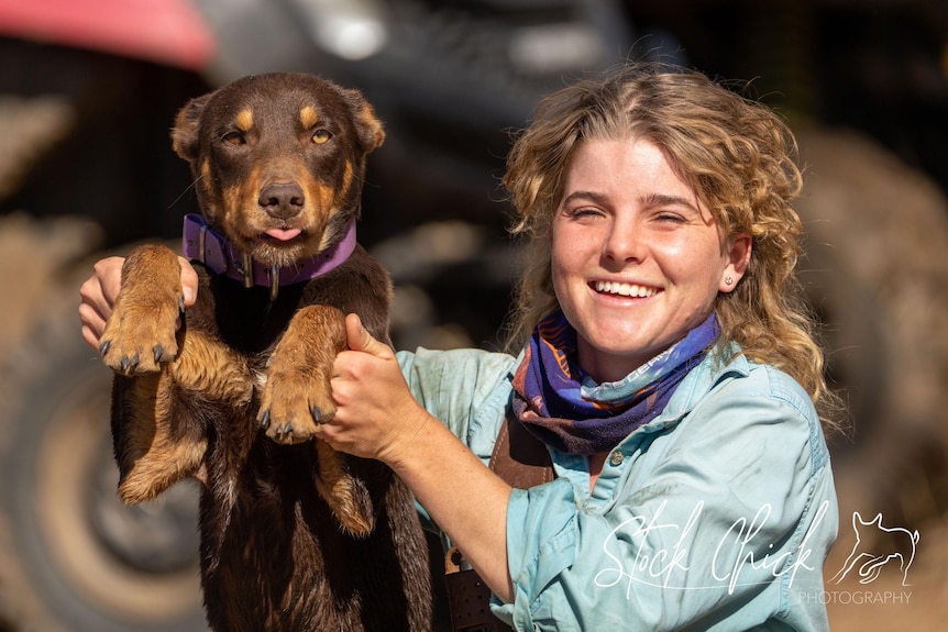 a young woman smiles at the camera while holding up a puppy