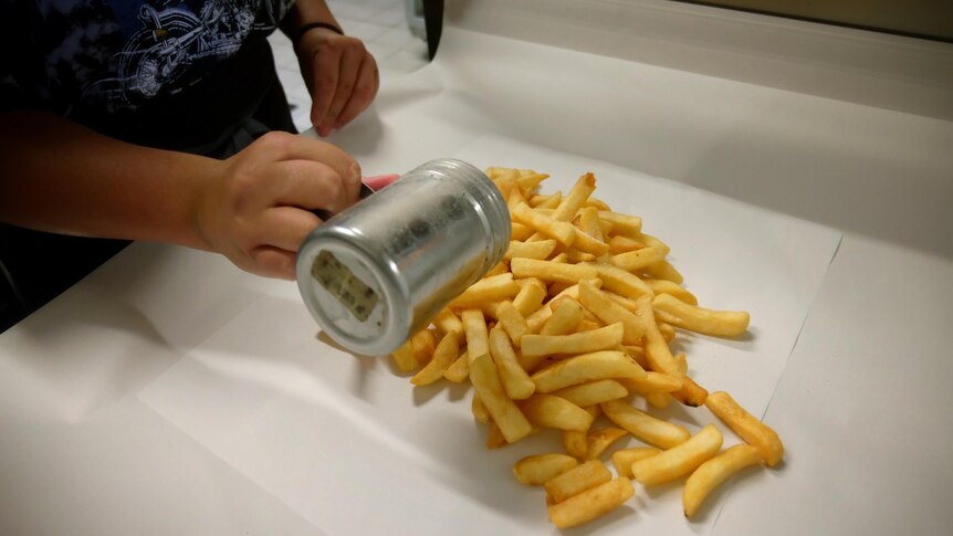 A pile of chips on some wrapping paper in a fish and chip shop
