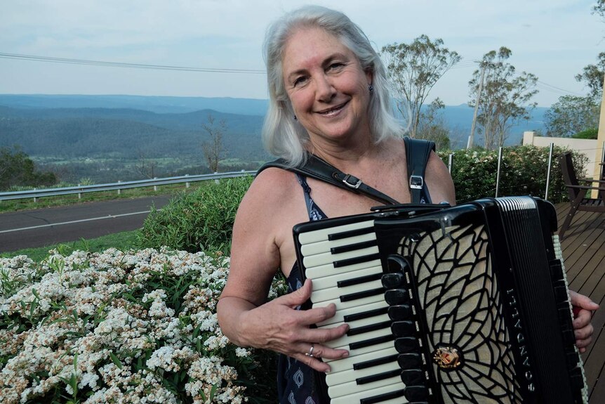 A woman holds a piano accordion