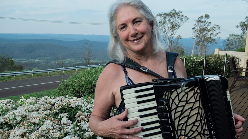 A woman holds a piano accordion