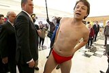 A Labor staffer wearing red speedos approaches Opposition Leader Tony Abbott