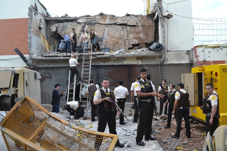 Guards and police inspect a vault that the assailants blew up early morning.