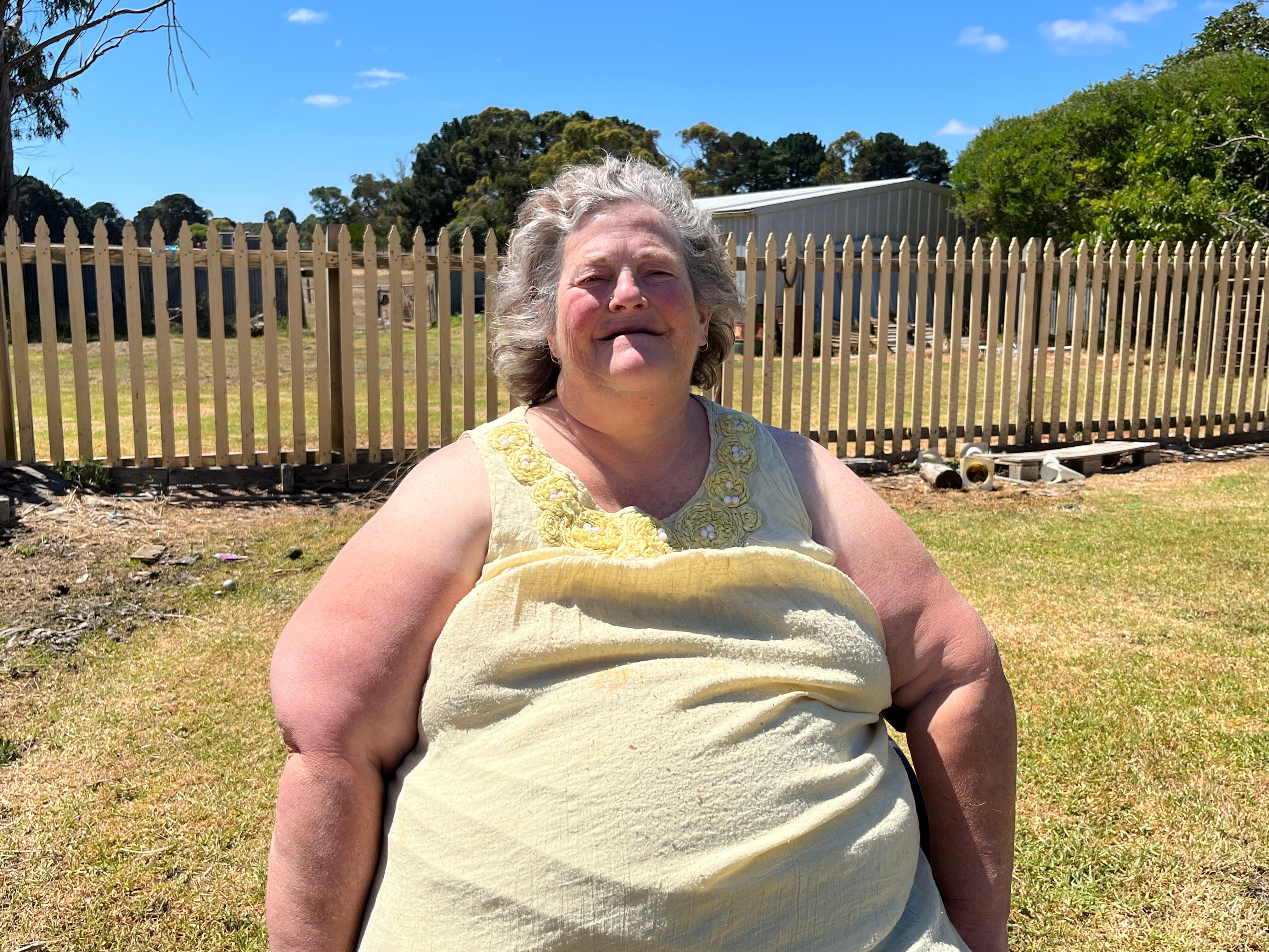 A woman sitting in a wheelchair in a backyard. 