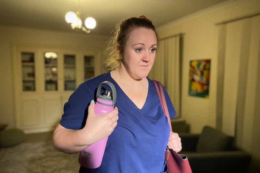 Kim Gallaher in a blue blouse with her bag and water bottle.