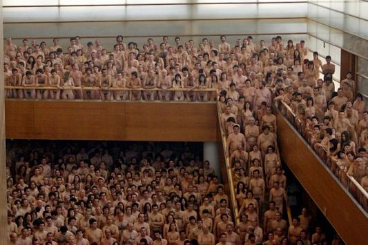 Naked people stand on a mezzanine, staircase and floor.