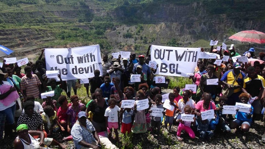 People supporting a rival mining consortium hold anti-BCL signs at the Panguna mine site.